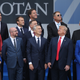 Leaders from NATO member and partner states view a military flyover.